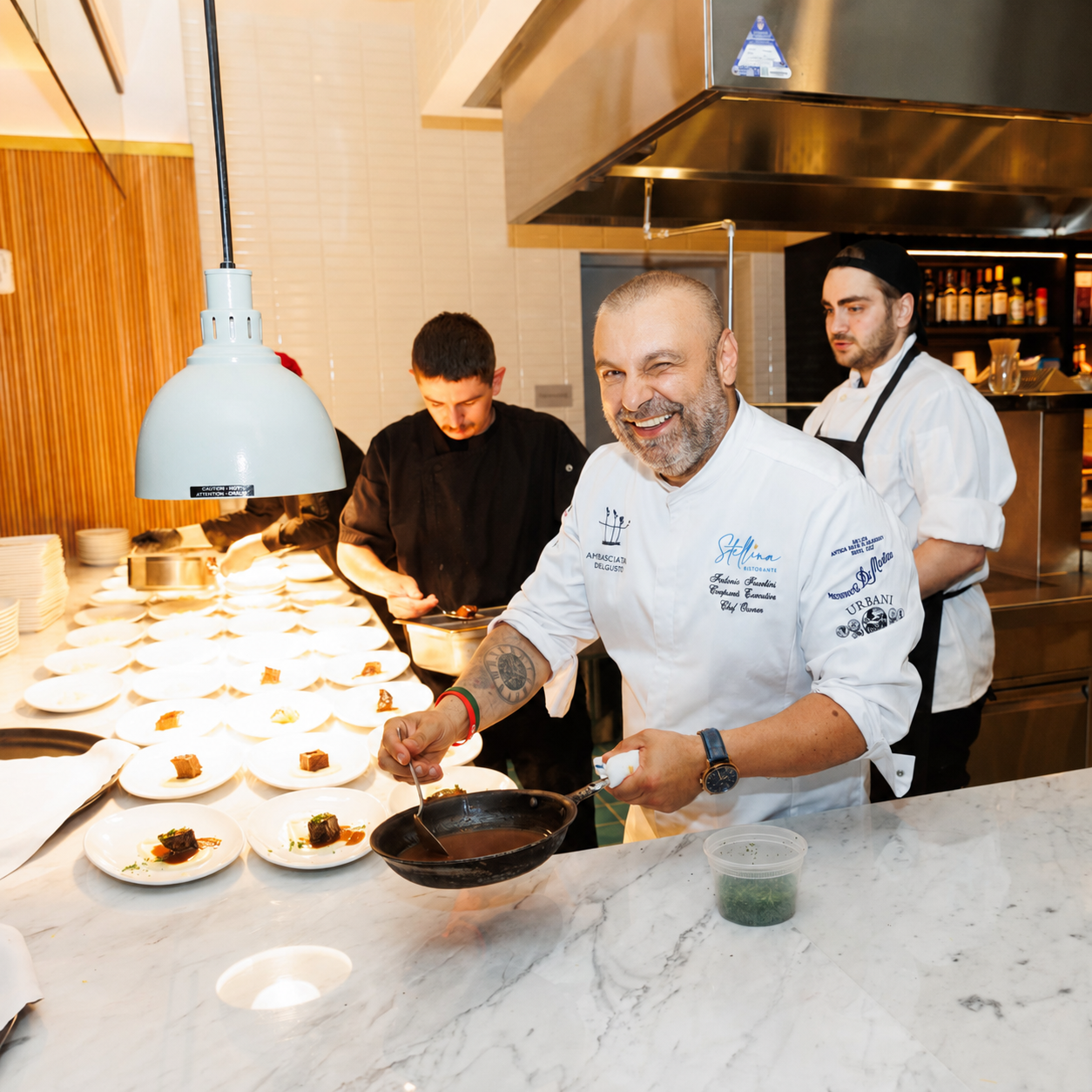 Chef Fabrizio Facchini finishing plates on a live chef station line